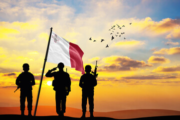 Silhouettes of soldiers with the Malta flag stand against the background of a sunset or sunrise. Concept of national holidays. Commemoration Day.