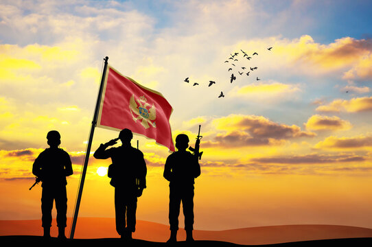 Silhouettes of soldiers with the Montenegro flag stand against the background of a sunset or sunrise. Concept of national holidays. Commemoration Day.
