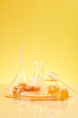 Natural raw beeswax is displayed alongside laboratory glassware. Concept of research and...