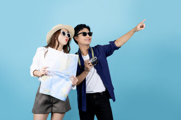 Happily smiling Asian tourist couple enjoying a summer vacation together on a bright blue background.