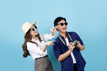 Surprised and excited Asian tourist couple in summer clothes on blue background.