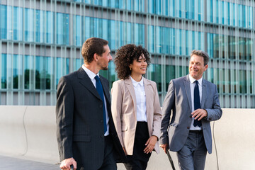 Business people meeting in a business park - Corporate businessmen and businesswoman bonding outdoors, colleagues meeting after work - Powered by Adobe