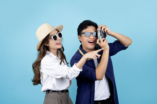Excited and surprised Asian tourist couple taking photos on blue background