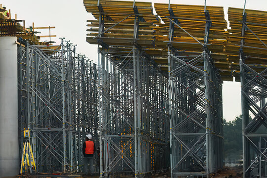 Construction of bridge. The road is currently under construction at several levels to increase traffic. Overpass road and support concrete structure with steel elements. Incomplete building site.