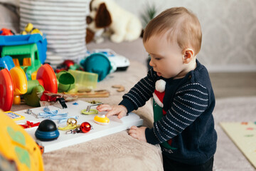Little boy cute child playful toddler playing different pile colorful toys balls decorated interior...