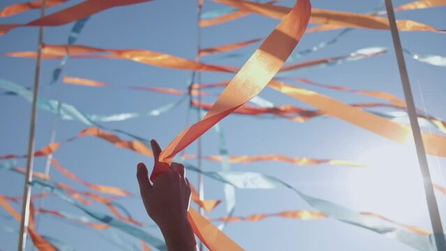 Woman hand playing with developing wind tapes. Person hands on the background of developing ribbons from the wind. Arm gestures of victory or celebration, activites or protests.