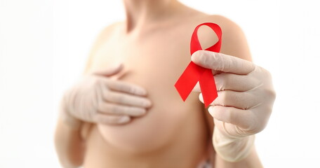 Female hand in gloves holding red ribbon cancer symbol breast closeup on doctor mammology clinic...