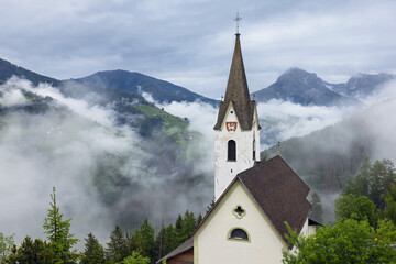 Fototapeta na wymiar Church on the background of the Italian Alps in the clouds