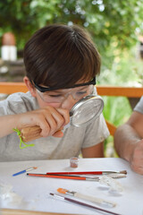 Happy child digging the dinosaur and having fun with archaeology excavation kit. Boy plays and...