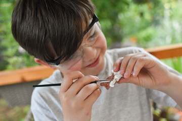 Happy child digging the dinosaur and having fun with archaeology excavation kit. Boy plays and...