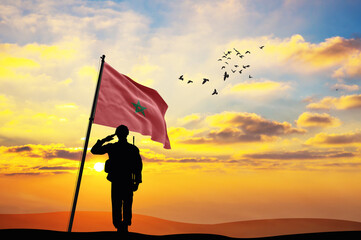 Silhouette of a soldier with the Morocco flag stands against the background of a sunset or sunrise....