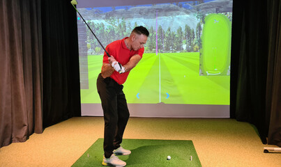 Professional male golfer holding club playing golf indoors on golf simulator