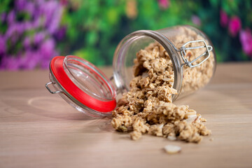 muesli spilled from a glass jar on a wooden table,A jar of home made granola
