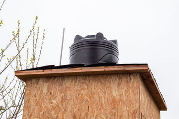 water tank is installed on a wooden shower cabin. Installation of a summer shower in the garden
