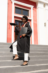  happy African girl student graduate against the background of the institute