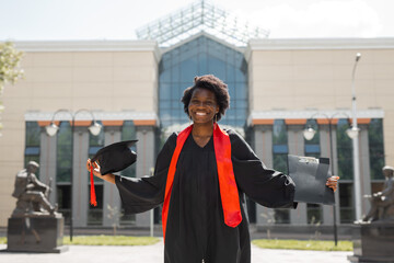  happy African girl student graduate against the background of the institute