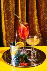 Variations of sweet and sour cocktails, alcohol drinks, stands on shiny silver tray on bar counter...