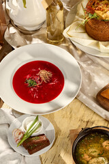 Borscht composition on a table with pork belly, garlic, and black bread, a Slavic dining staple