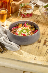 Hearty salad with roasted potatoes, shredded beef, onions, and smoked sour cream in a modern bowl