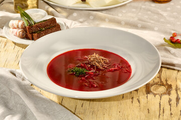 Traditional borscht served with rye croutons, sliced pork belly, and sour cream in bright sunlight