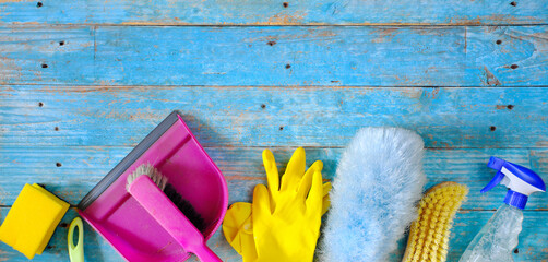 Flat lay spring cleaning composition with cleaning supplies, tools and blue wood background,...
