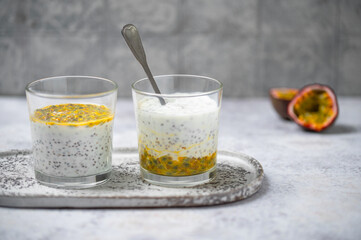 Chia pudding with passion fruit puree and yogurt in a glass on a grey background. Healthy...