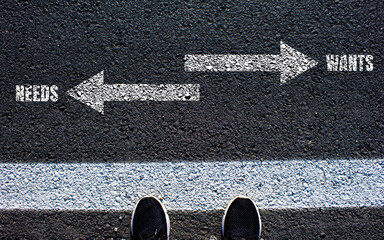 Wants or needs symbol on asphalt road. Conceptual photo.