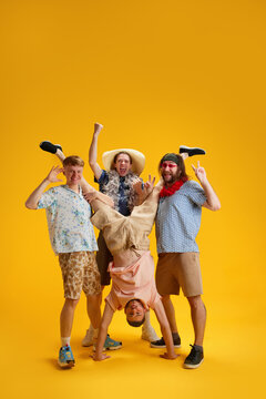 Emotional happy young men, friends in stylish clothes having fun together, relaxing, dancing on summer vacation against yellow background. Concept of leisure, emotions, friendship, fun, bachelor party