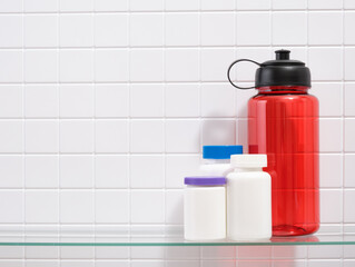 A red sports shaker for water and medical jars of vitamins. Copy space for text.