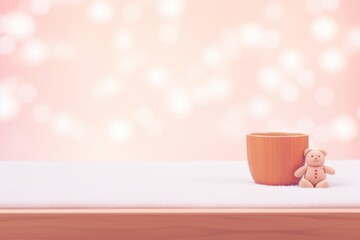 Wooden cup of tea on a table with small teddy bear soft toy and pink background