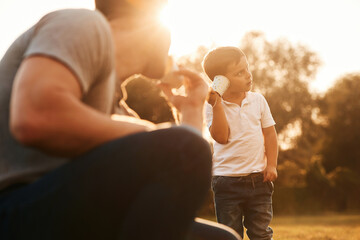 With string can phone. Father and little son are playing and having fun outdoors - obrazy, fototapety, plakaty