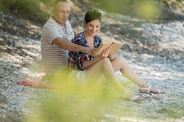 couple relaxing on the pebbles with a book
