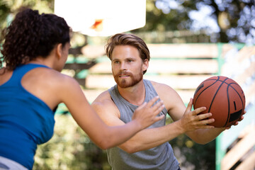 beautiful couple flirting and playing on an asphalt basketball court