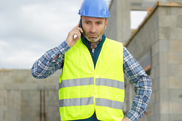 male builder foreman architect on building site using phone