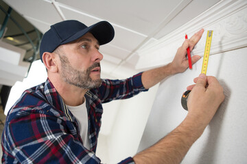 workman measuring ornate ceiling cornice © auremar