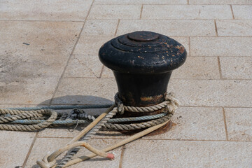 Stahl-Poller in einem Hafen (harbour - mooring bollard) / Poller mit Tauwerk auf dem steinernen Kai