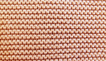 Close up background of knitted  wool fabric knitwear texture.Peach fuzz - color of the year 2024.Selective focus.