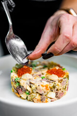 Professional chef cooking Salad Olivier in restaurant kitchen