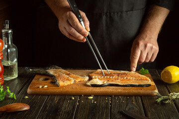 A professional chef prepares a steak from fresh salmon fish on the kitchen table. Fish for cooking...