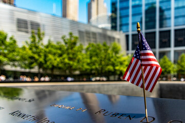 Photo of an American flag at the World Trade Center memorial, a tribute to the victims of the September 11 terrorist attack in New York (USA). - obrazy, fototapety, plakaty