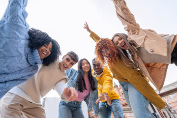 Youthful friends extend hands towards camera in a lively selfie, full of vitality and playful...