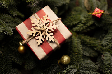 Christmas gift wrapped in striped craft paper and decorated with wooden snowflake, surrounded with...