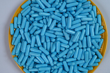 Yellow plate full of blue medicine capsules representing drug overdose