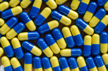 full background of many pills in blue and yellow capsules forming a plot of quantity of medicines
