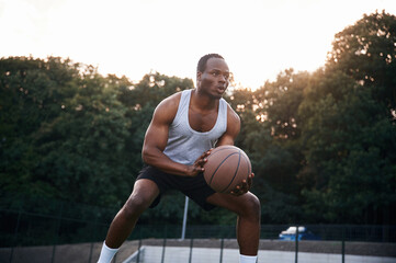 Playing the game. Young black man is with basketball ball outdoors