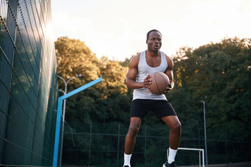 Photo in motion. Young black man is with basketball ball outdoors