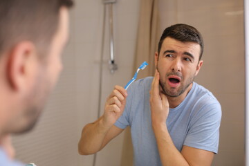 Man experimenting pain while brushing his teeth  - obrazy, fototapety, plakaty