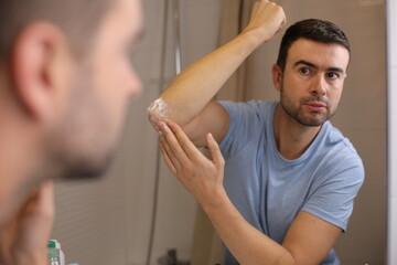 Man moisturizing his dry elbows 