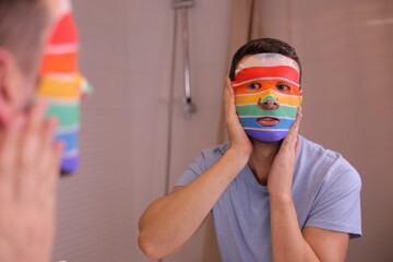 Man using a moisturizing face mask with the rainbow colors 