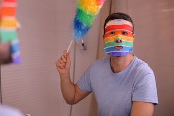 Proud gay man cleaning the house while doing a facial cosmetic treatment  - obrazy, fototapety, plakaty